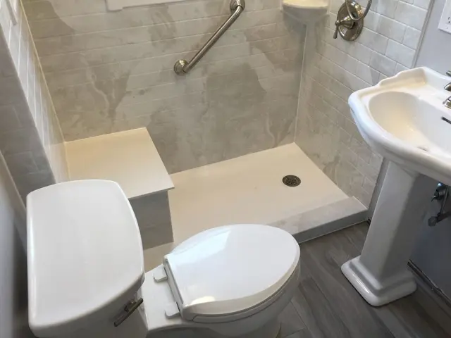 Accessible shower base with grab bar and low-profile entry